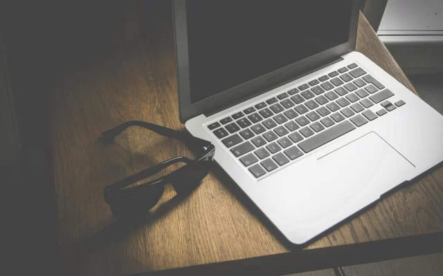 A MacBook Air and sunglasses on a wooden desk, representing the digital landscape of ePrivacy Regulation.