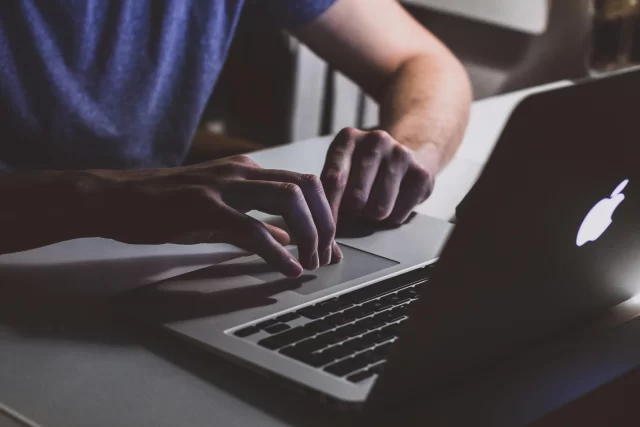 Close-up of a person typing on a laptop, emphasizing the security risks involving Personally Identifiable Information.