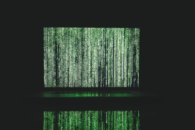 A laptop screen displaying cascading green digital code, symbolizing a cybersecurity Data Breach.