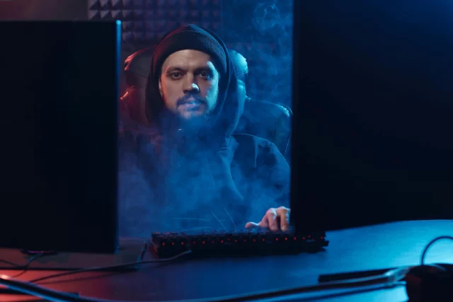 A hacker in a hoodie surrounded by blue smoke, representing the security risks of a Password Leak.