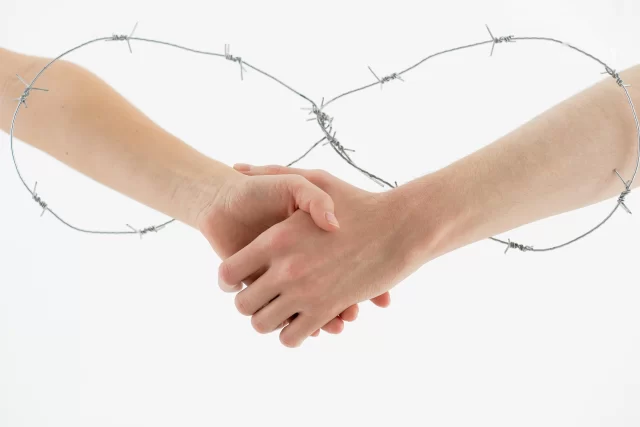 A handshake enclosed in a heart formed from barbed wire, symbolizing the secure agreements and regulatory boundaries of General Data Protection