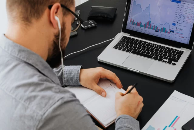 A professional analyst studies financial charts and takes notes as part of a DPO strategy.