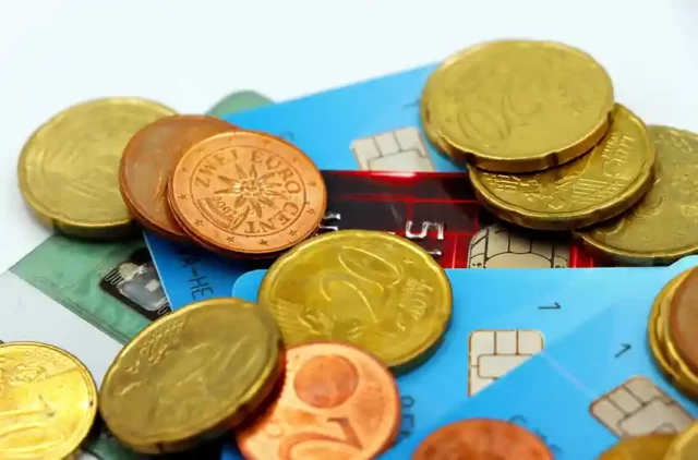 Euro coins scattered over various smart chip credit cards representing the payment card industry.