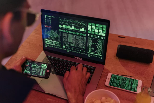 A developer working on a laptop and mobile devices to secure data for PCI and DSS compliance.