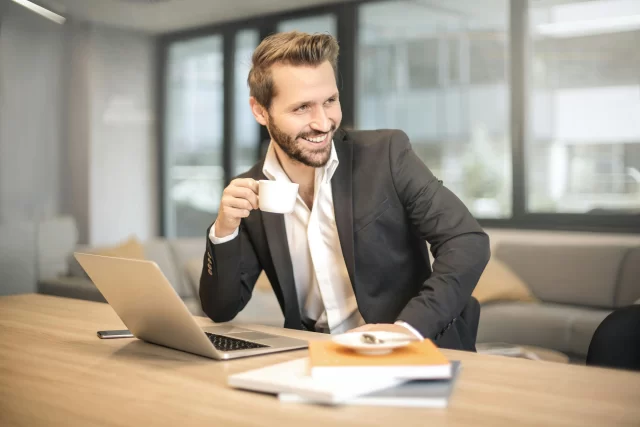 A professional smiling man using a laptop to research Swiss cloud offerings.