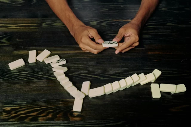 Hands arranging a domino chain, illustrating strategic planning in Switzerland's Payment Card Industry.
