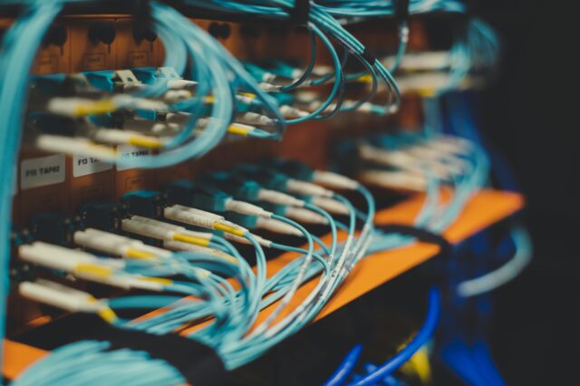 Light blue fiber optic cables connected to a server rack supporting Google Cloud Computing in Switzerland.