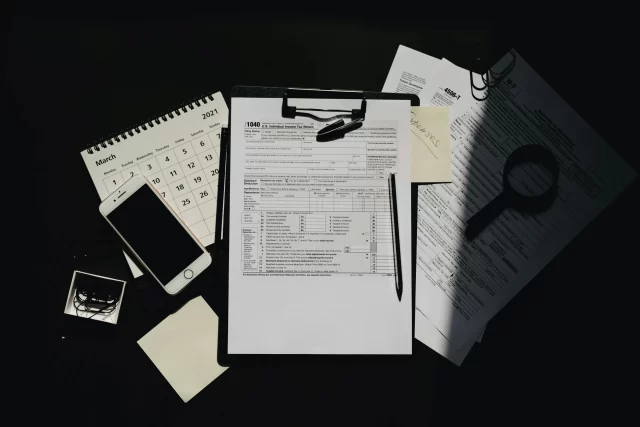 Tax documents and a smartphone on a desk, representing the financial risks of A Data Breach.