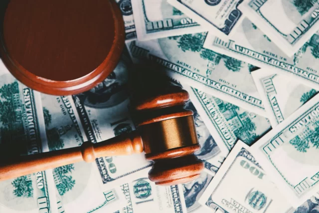 Wooden judge's gavel resting on a pile of US dollar bills, representing legal costs for GDPR Compliance in Switzerland.