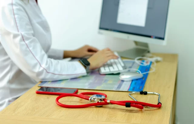 Healthcare professional working on a computer to ensure data compliance with GDPR in Switzerland.