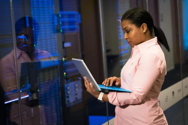 IT professional reviewing data on a laptop in a secure Swiss Cloud Computing server room.