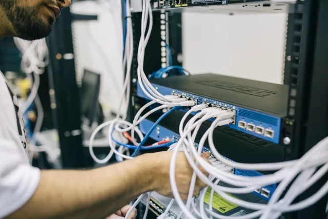 A technician manages network cabling, representing the infrastructure behind a cloud in Swiss cloud computing.